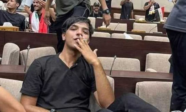 صورة أثارت ضجة في العراق..  متظاهر  يدخن السجائر يجلس على كرسي رئيس البرلمان ويردد: «الشعب هو القائد»