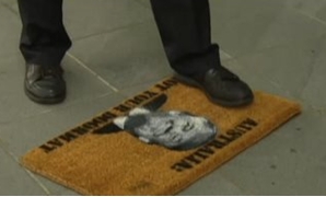 سيناتور أسترالى يدهس بقدمه "ممسحة أرجل" عليها صورة ترامب